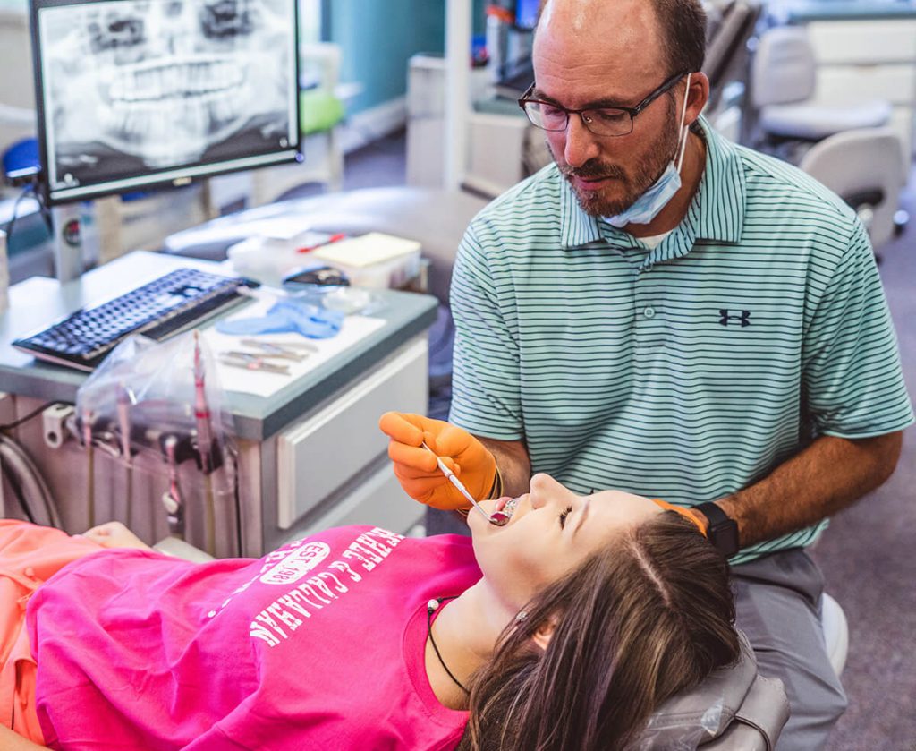 orthodontist-doctor-chad-callahan-checks-female-patient-during-braces-exam-in-pace-florida-office
